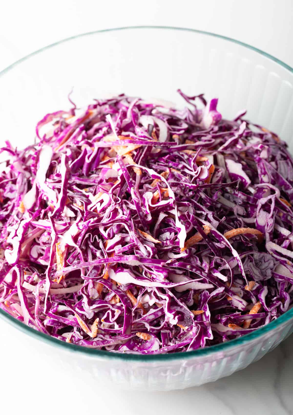 Overhead shot of a red cabbage slaw recipe in a glass bowl.