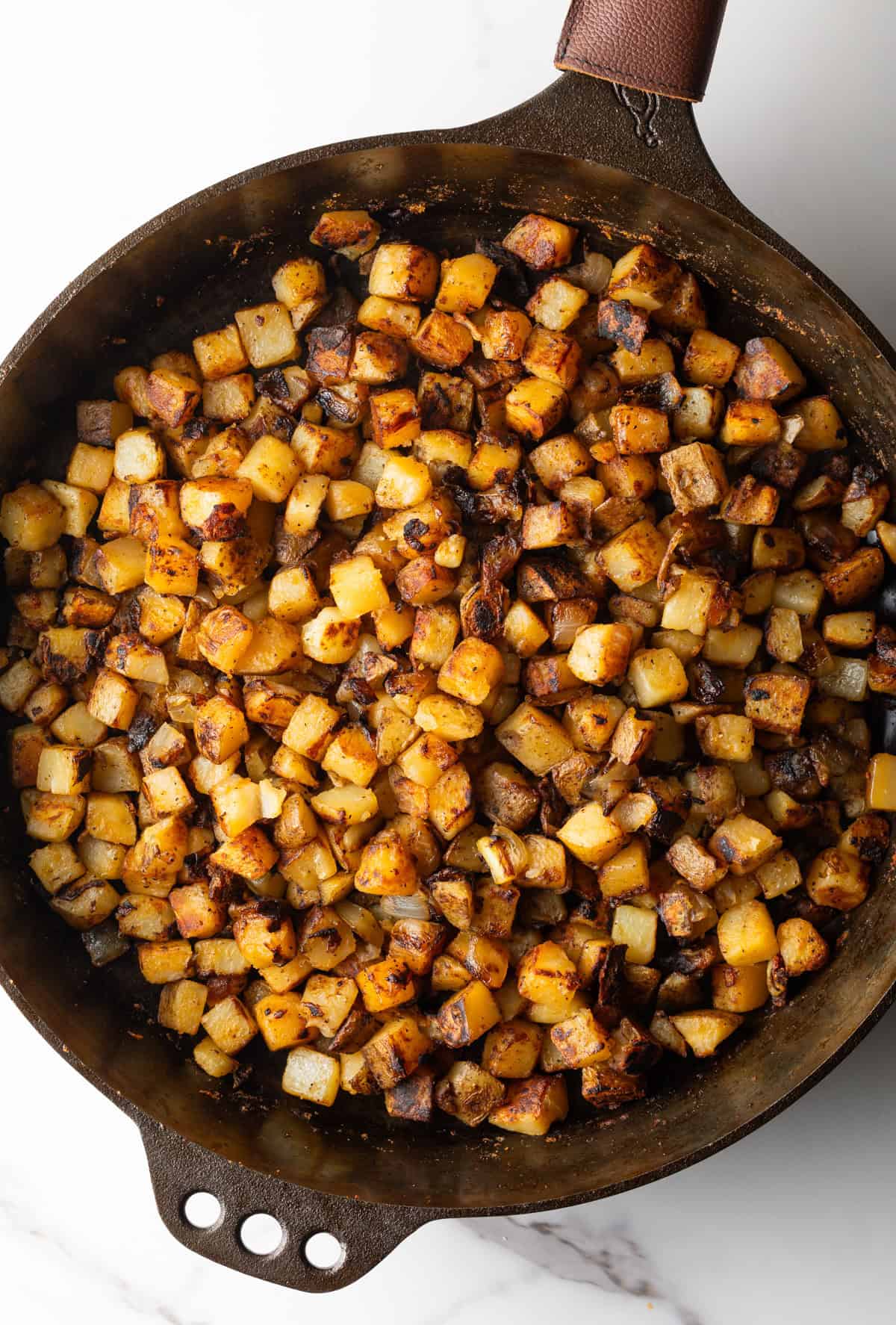 Crispy breakfast potatoes in a black skillet.