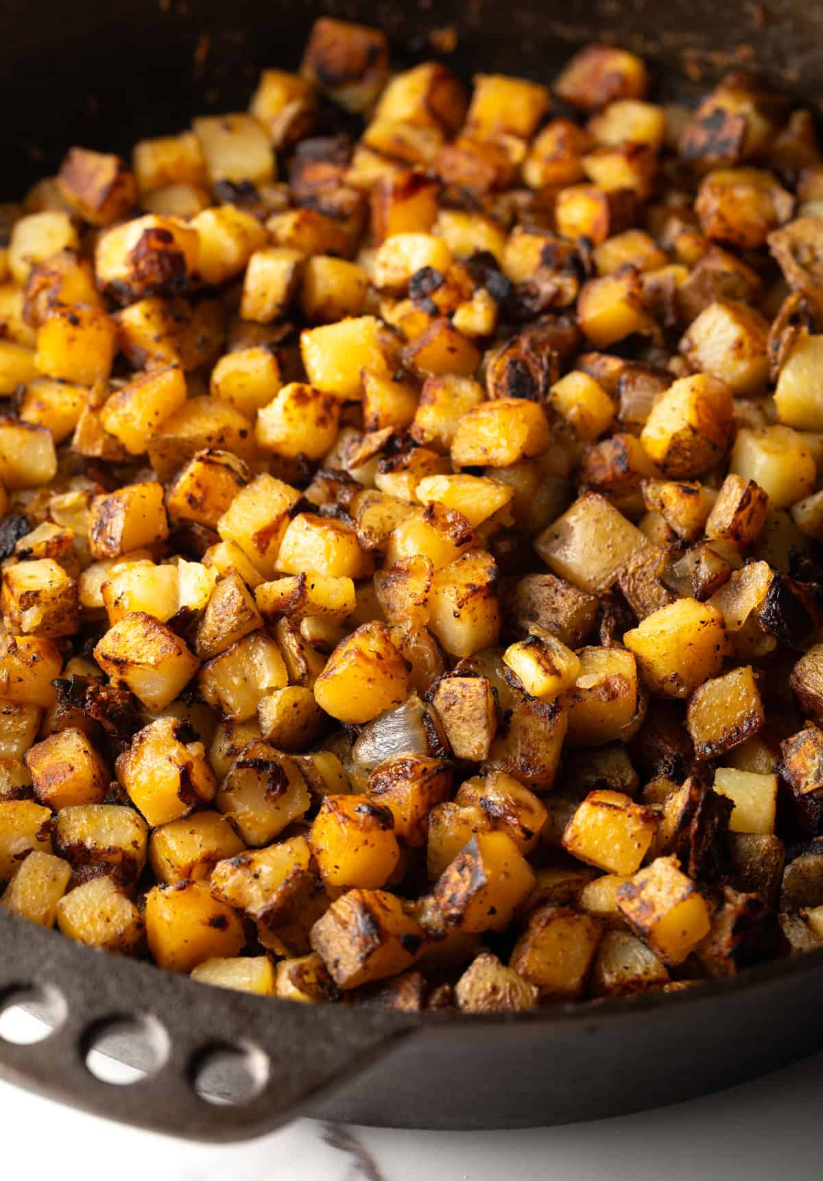 Crispy skillet fried potatoes in a black skillet.