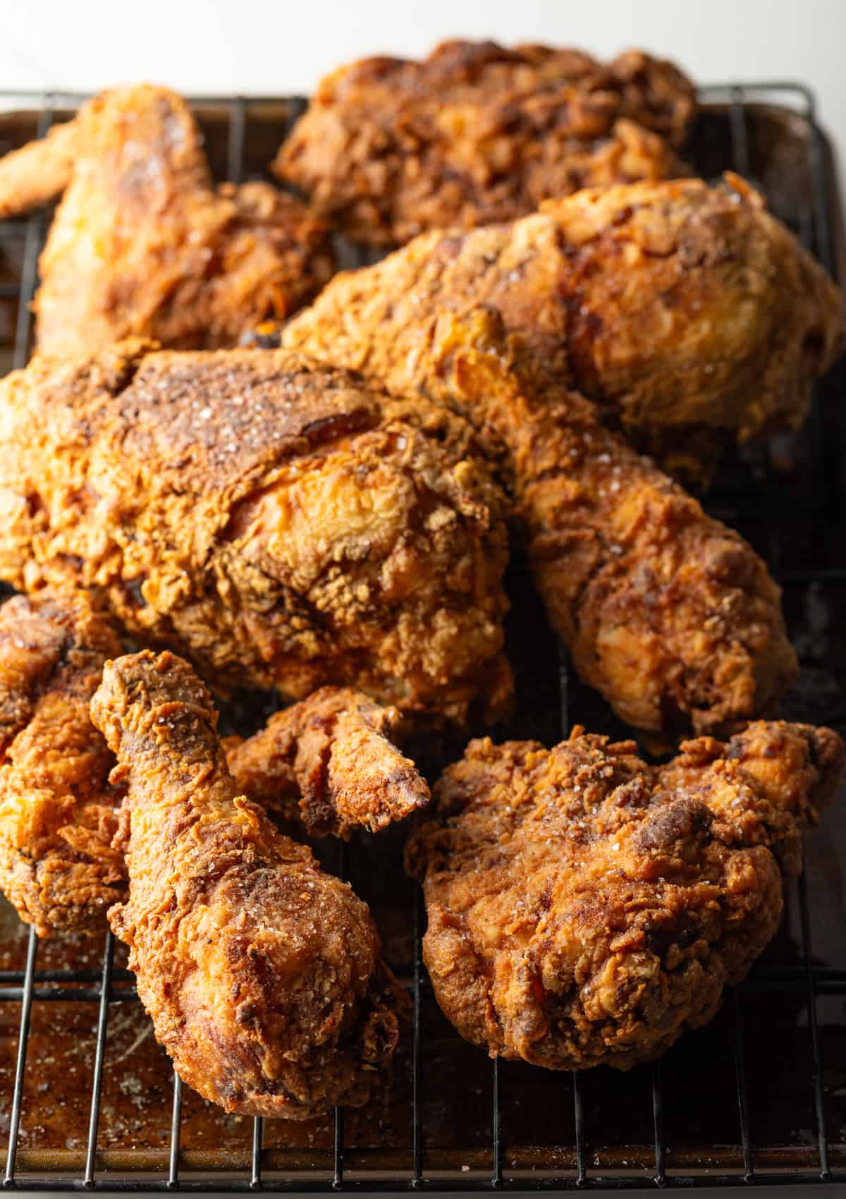 Crispy southern fried chicken cooked in a cast iron skillet draining on a roasting tray.