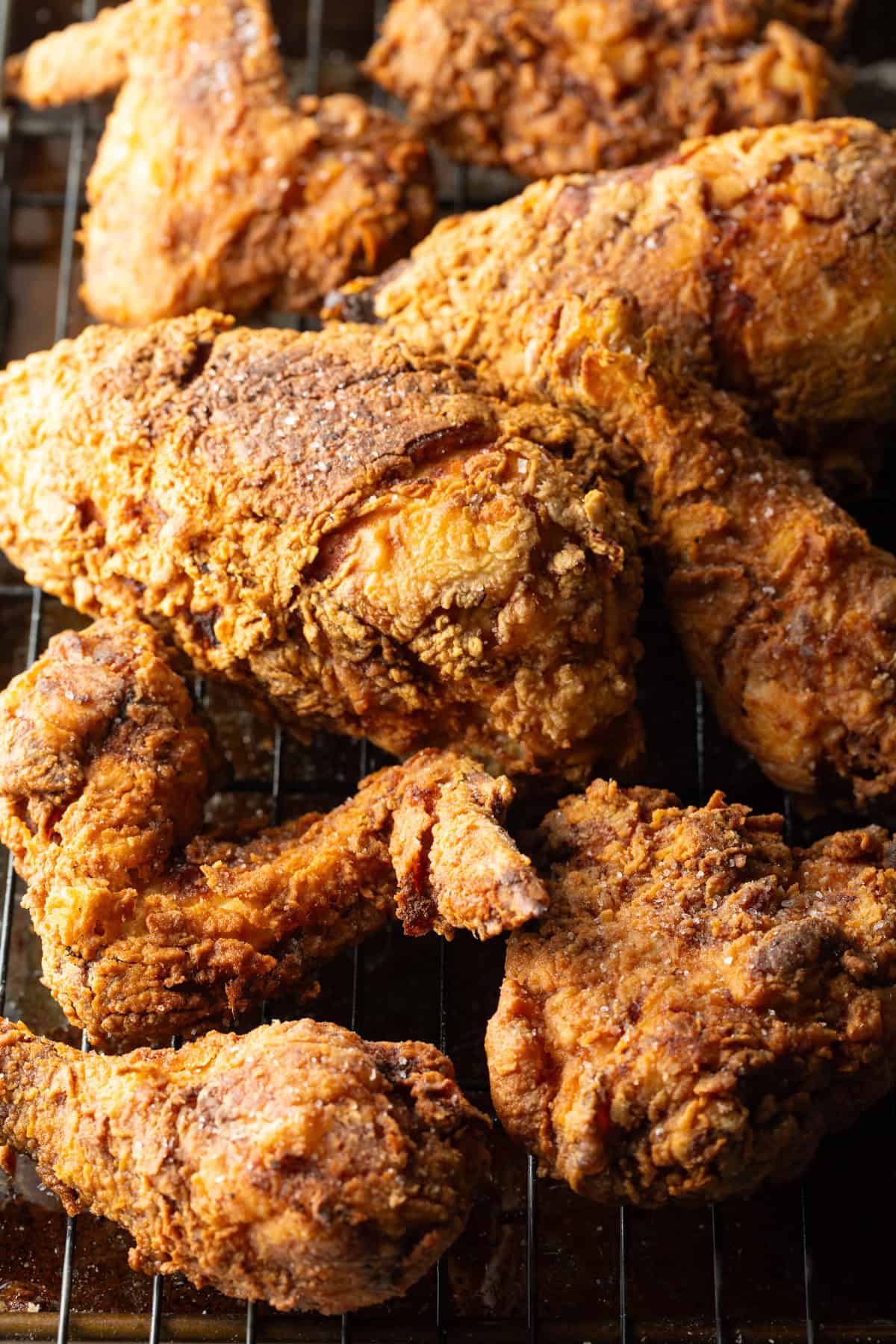 Crispy southern fried chicken cooked in a cast iron skillet draining on a roasting tray.