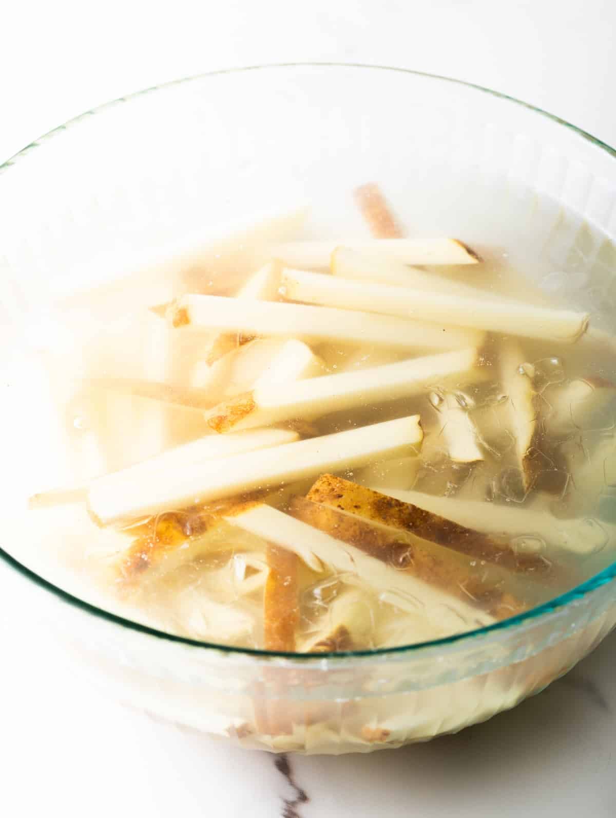 Raw potato slices sitting in an ice water bath.