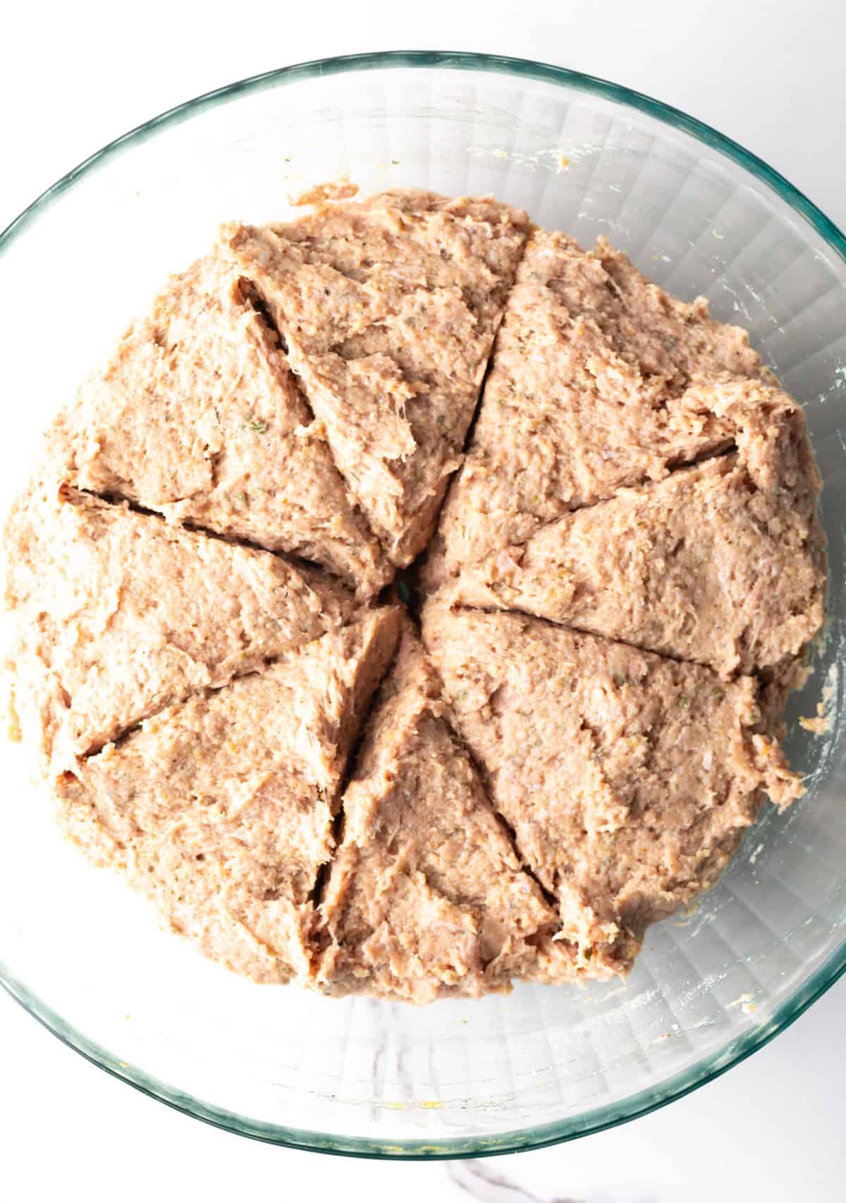 A turkey burger mix in a glass bowl, divided into eight sections.