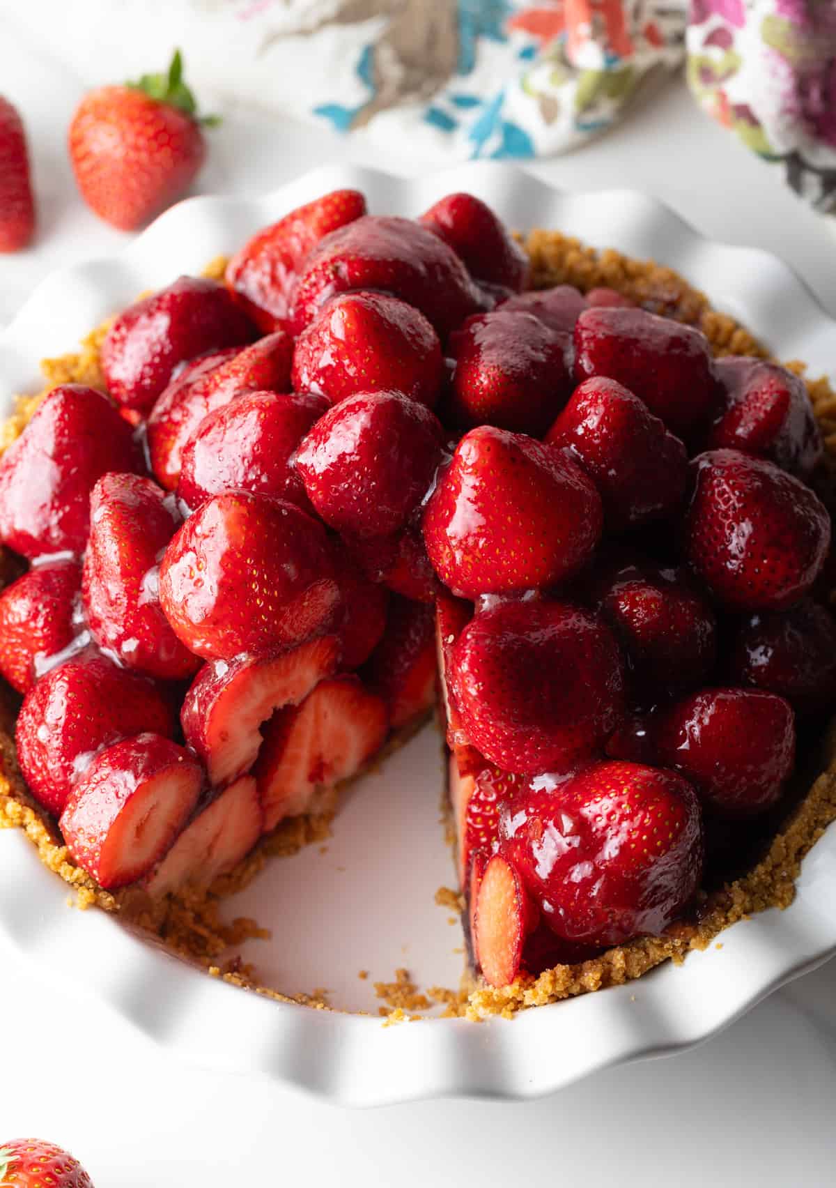 A no bake fresh strawberry pie in a pie pan with a slice taken out.
