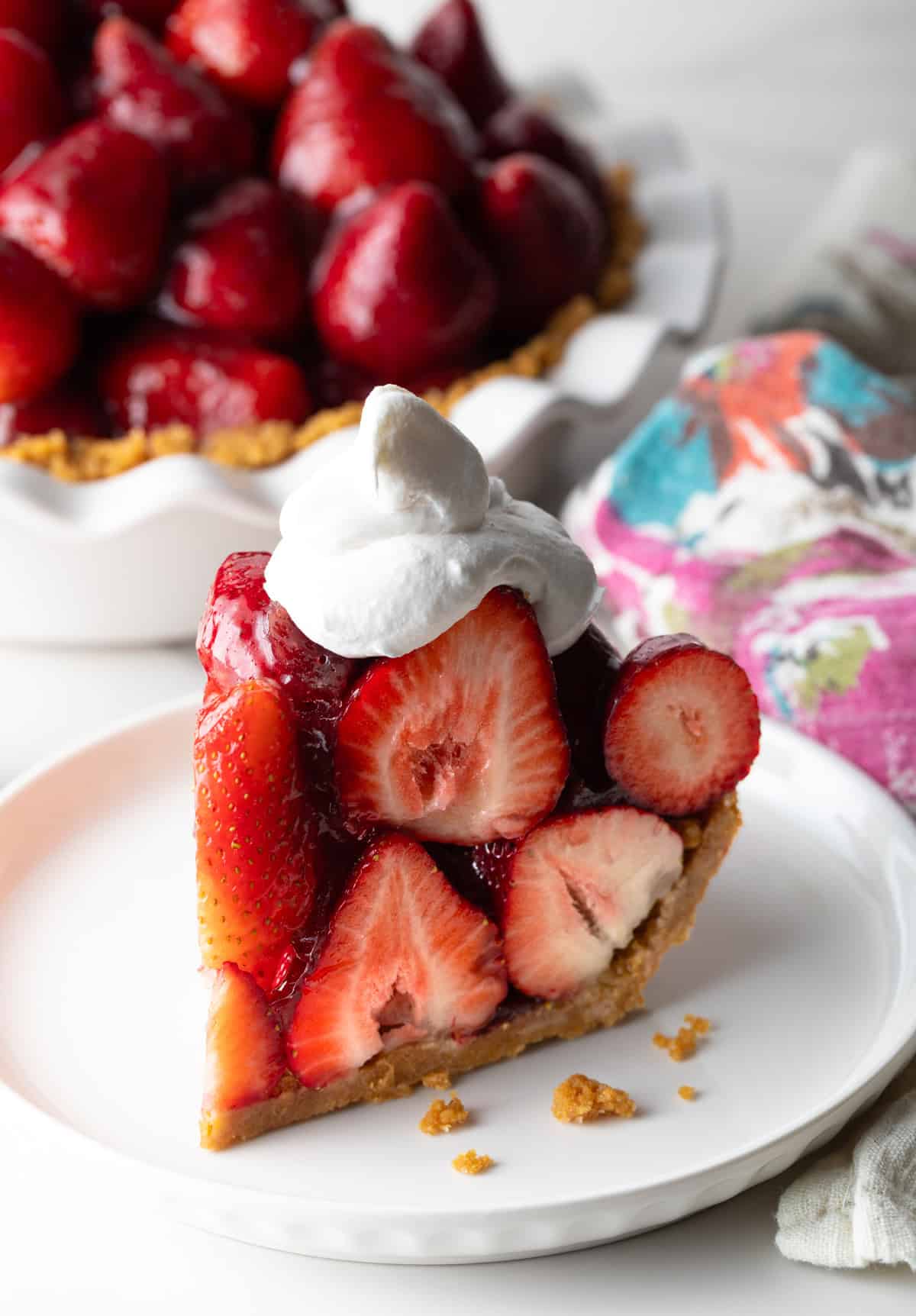 A slice of easy no-bake strawberry pie topped with whipped cream, sitting on a white plate.