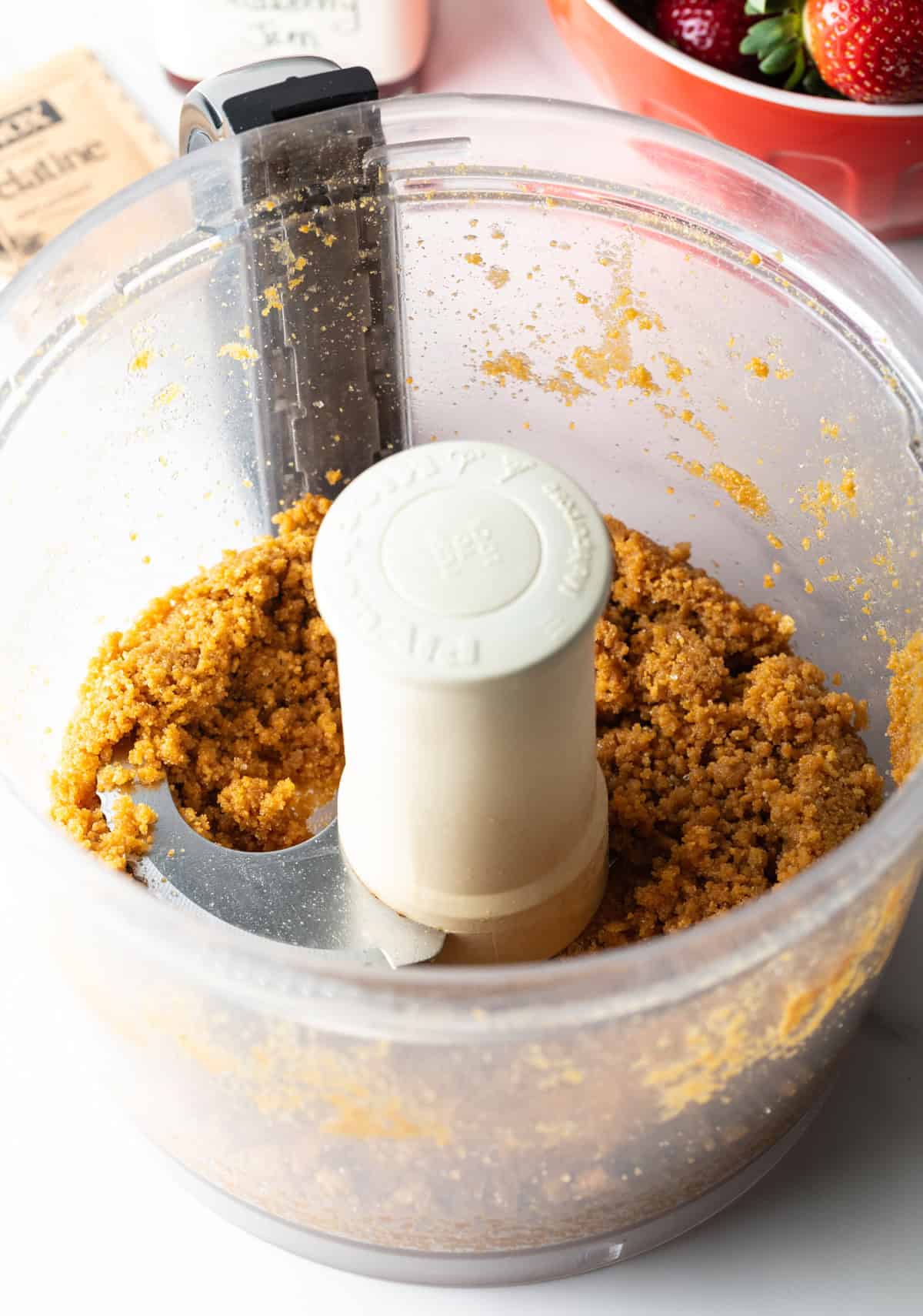 Ginger snap cookies are being pulsed in a food processor to make a crust for a strawberry pie recipe.