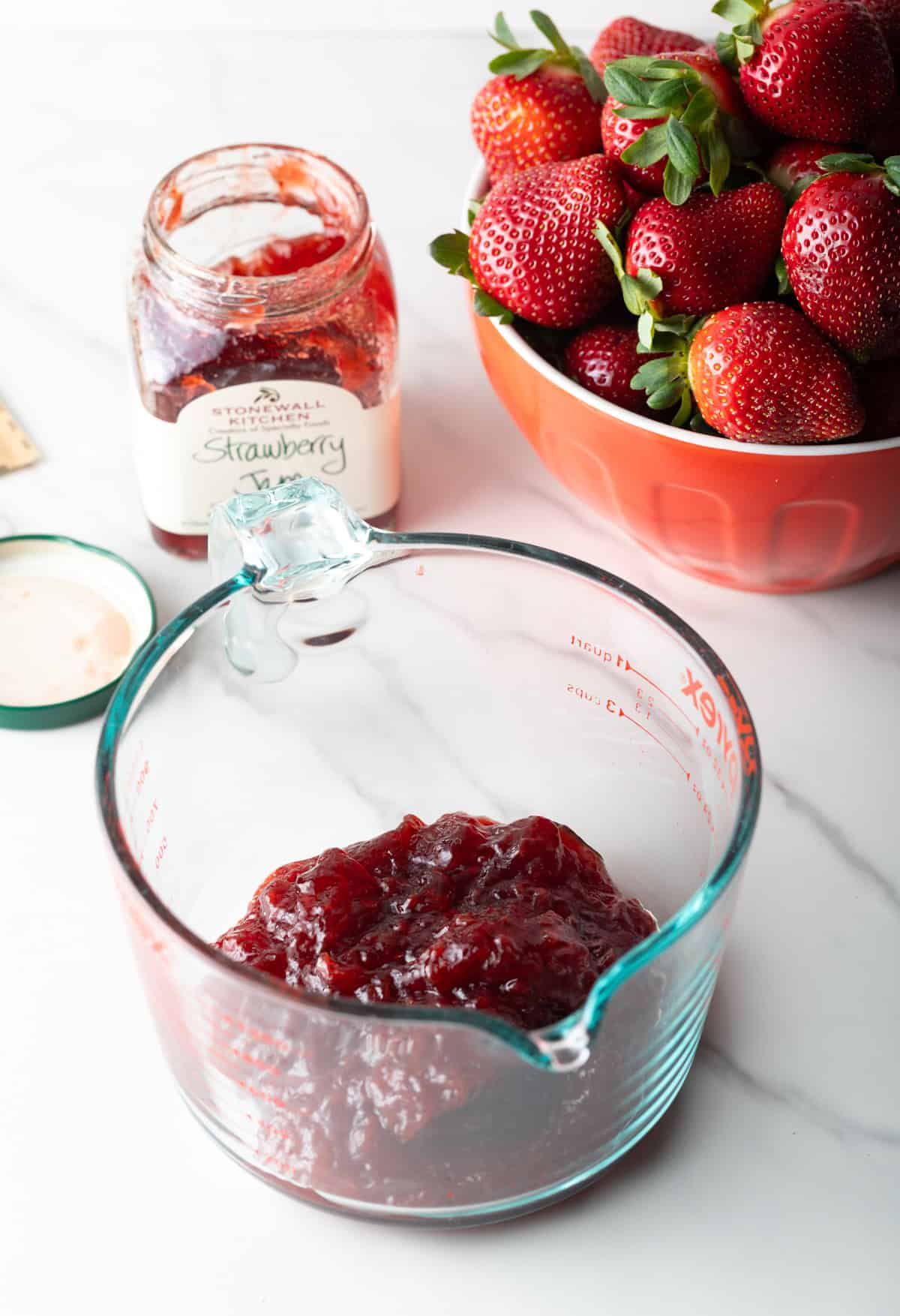 A strawberry jam and gelatin mixture in a glass measuring bowl.