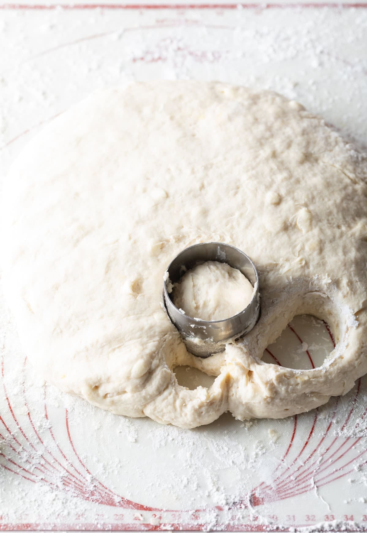 Angel biscuit dough on a floured surface that is being cut with a circular biscuit cutter.