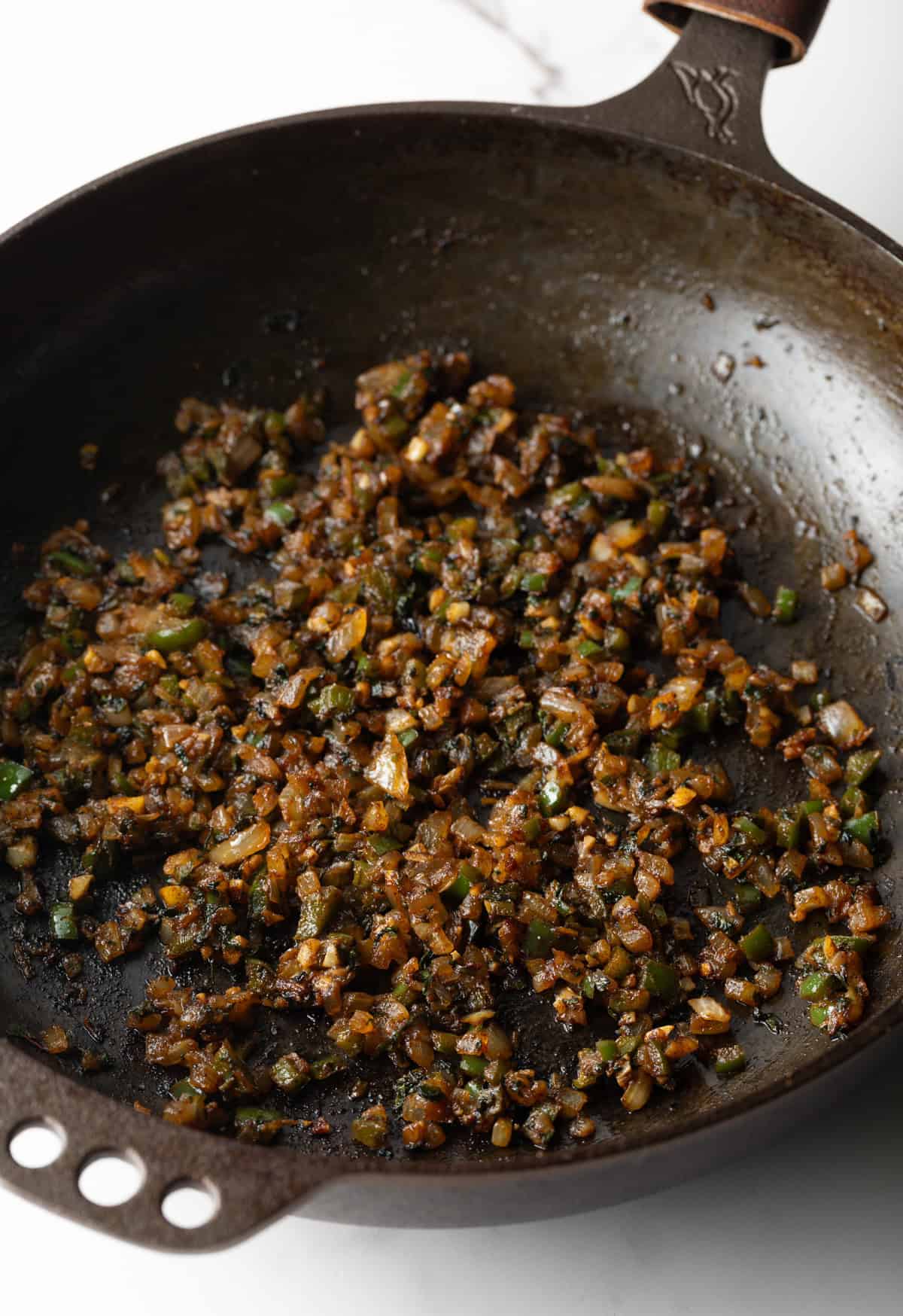 Vegetables are sautéing in a black skillet.
