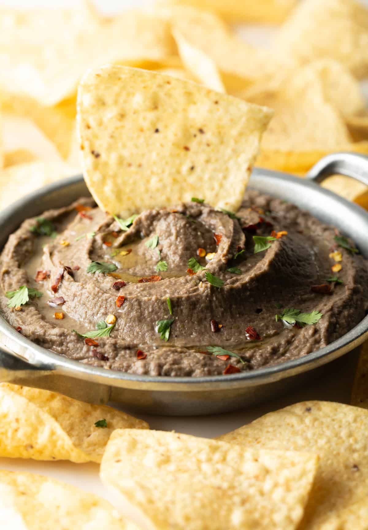 A tortilla chip is being dipped into a easy homemade black bean dip recipe.