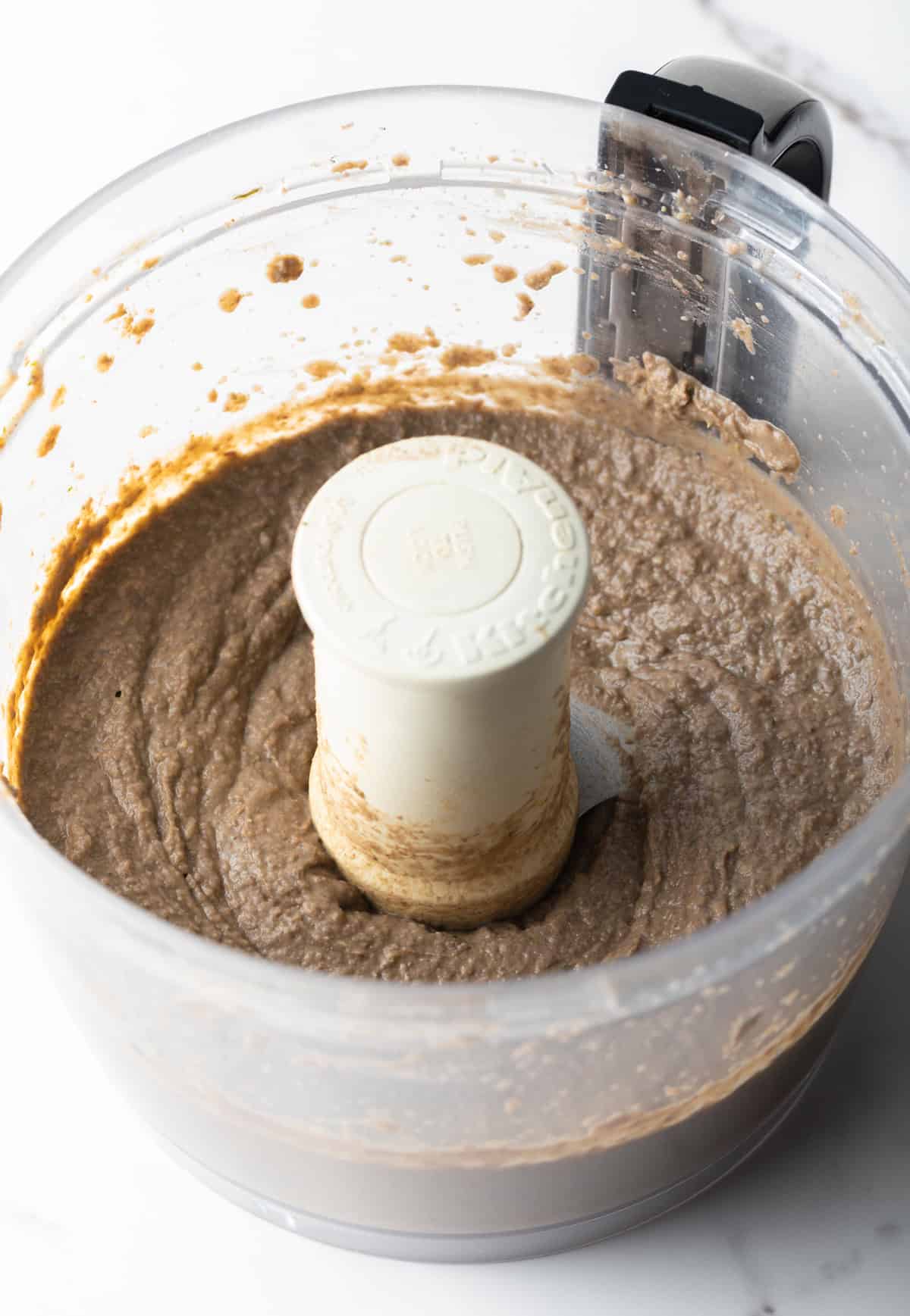 A black bean dip and veggie mixture have been pulsed until smooth in a food processor.