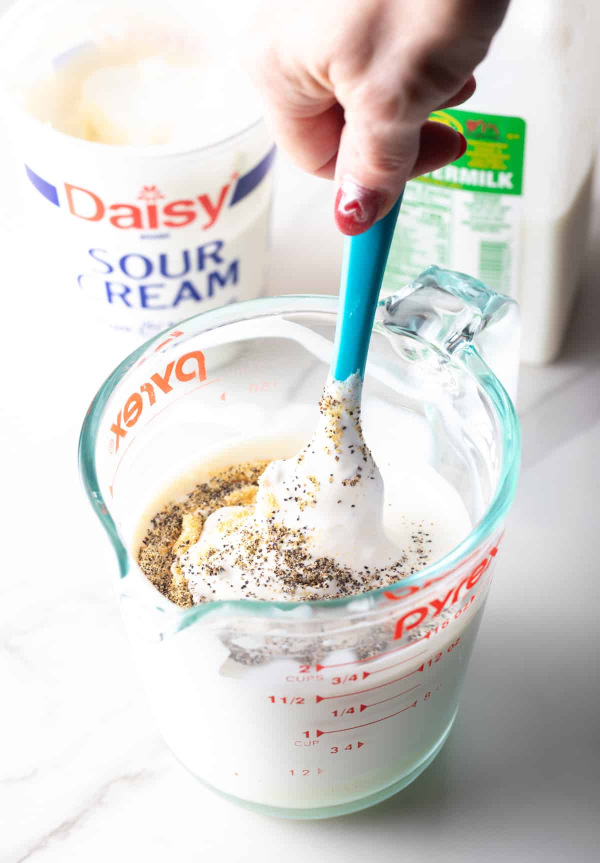 A blue cheese dressing mixture in a glass measuring bowl.