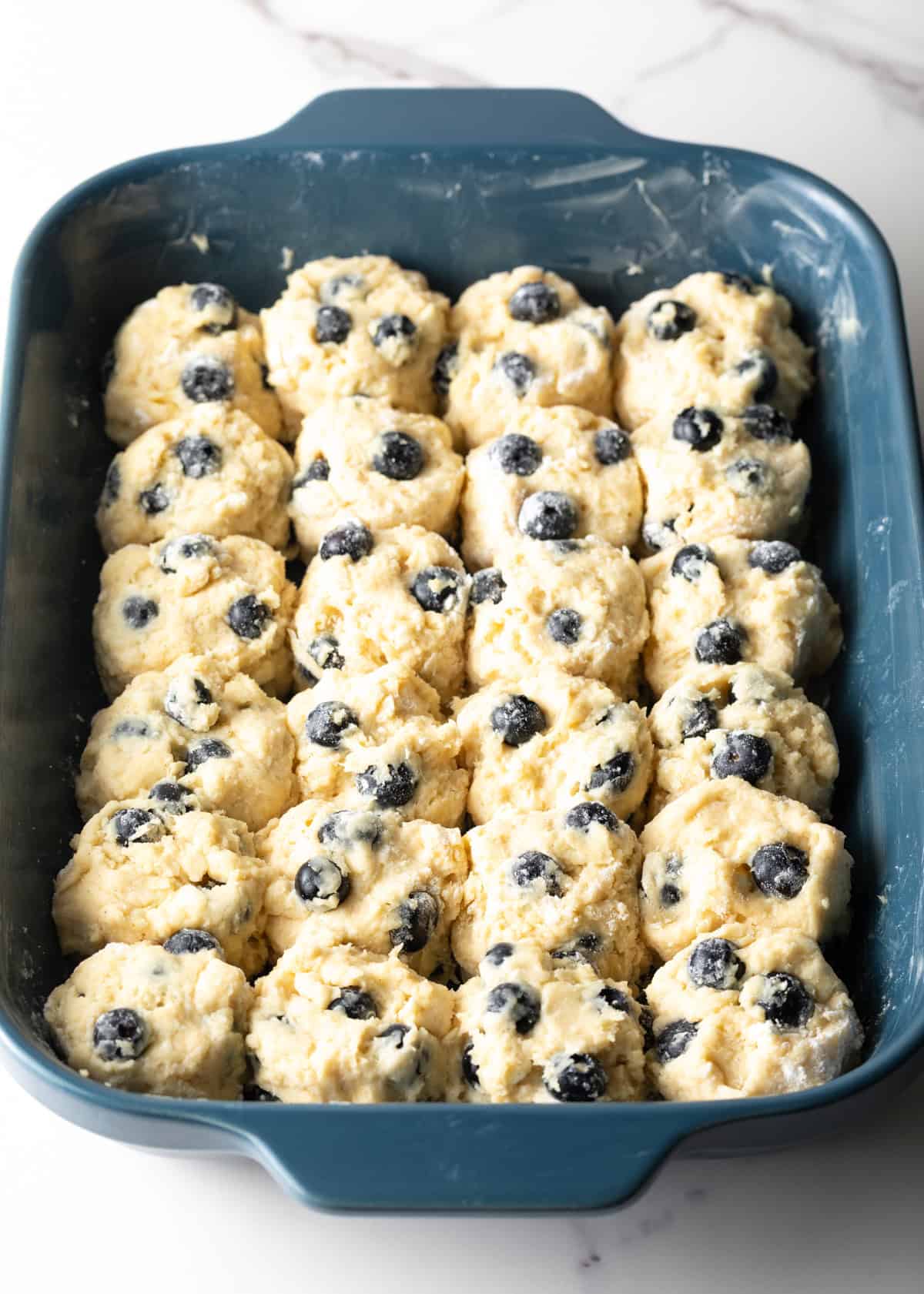 Unbaked blueberry biscuits arranged in a baking dish.