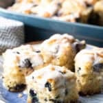 A blue plate with four homemade blueberry biscuits topped with lemon glaze.
