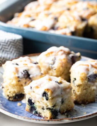 A blue plate with four homemade blueberry biscuits topped with lemon glaze.