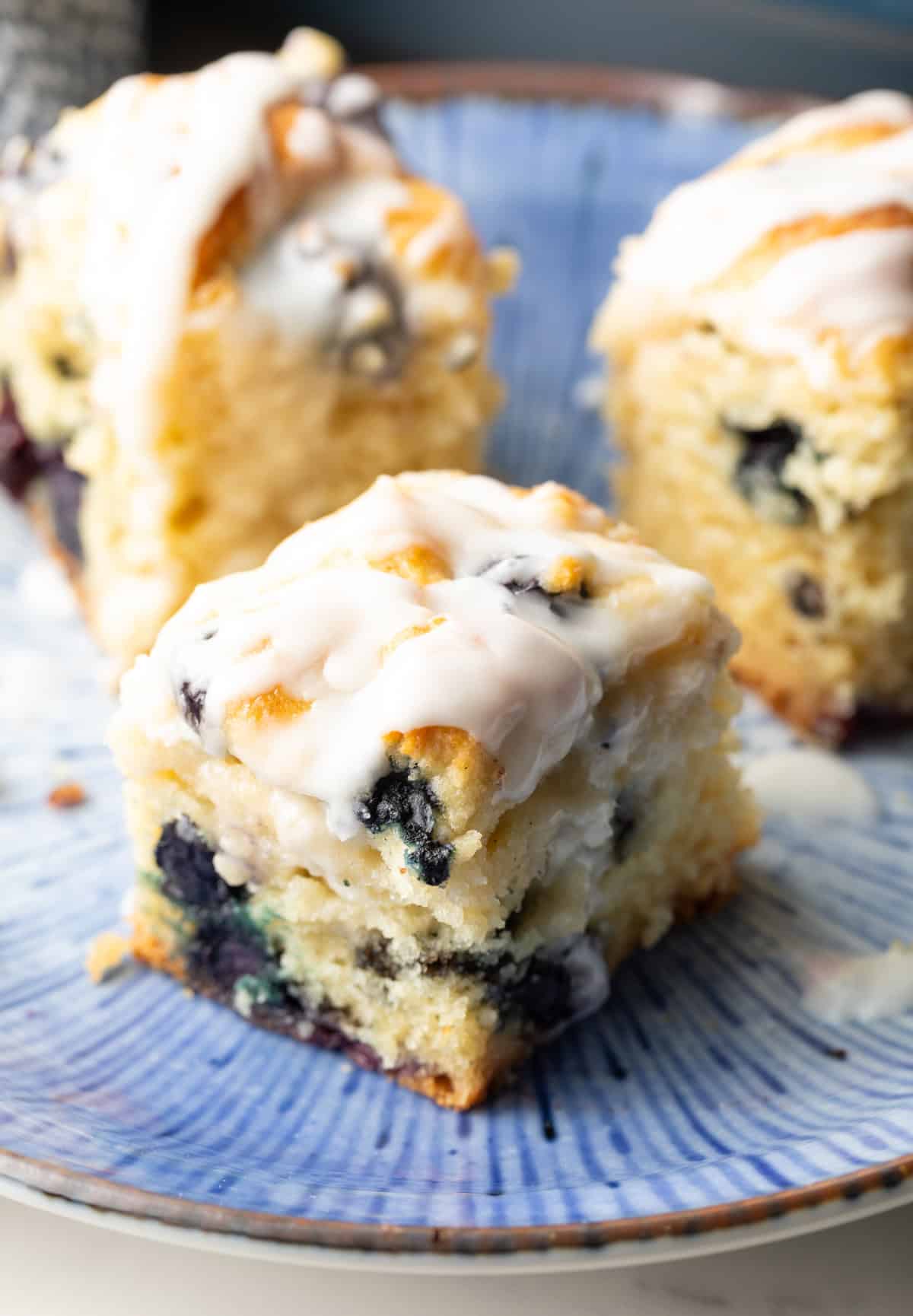 A close-up shot of a fluffy blueberry biscuit sitting on a blue plate.