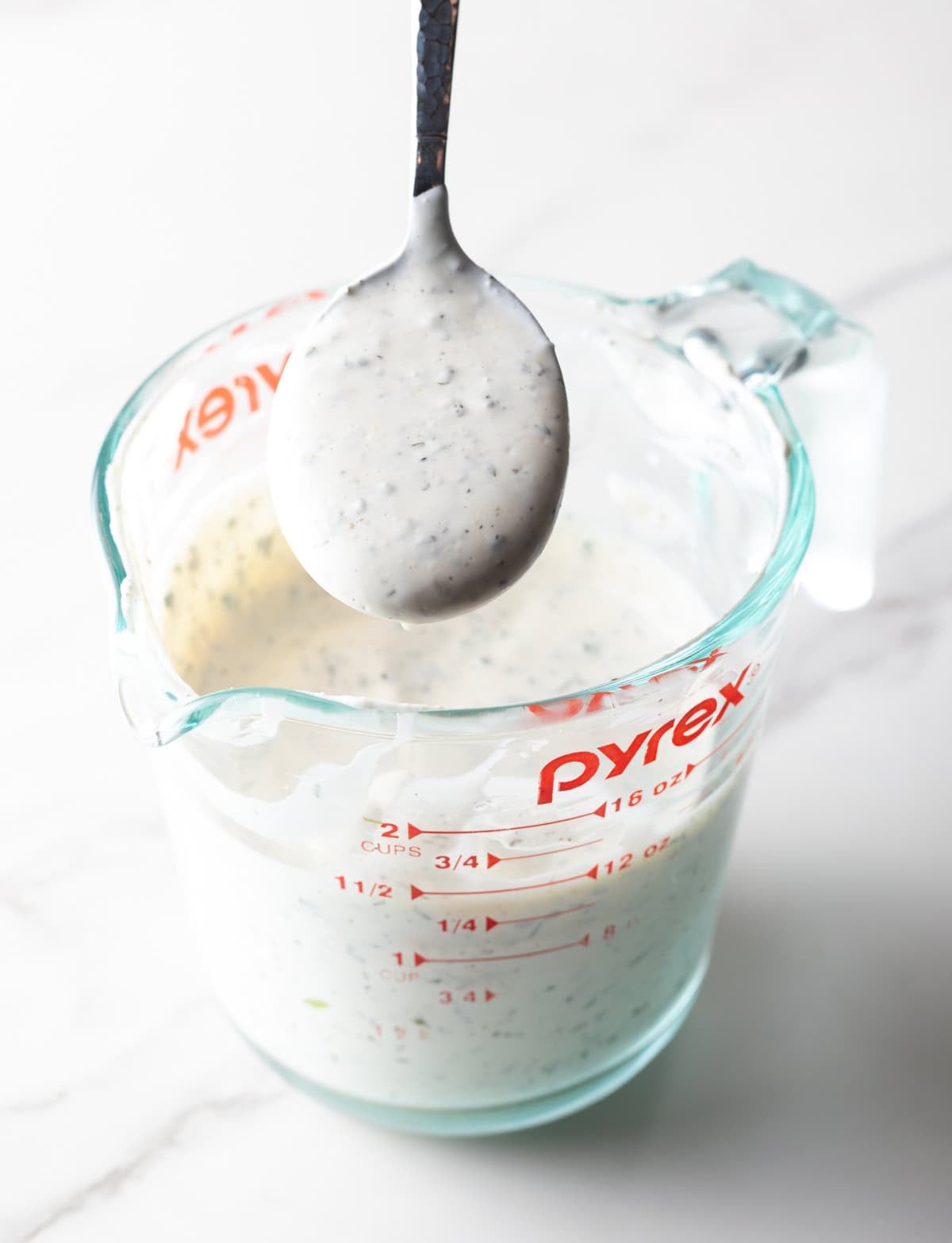 ranch dressing recipe made in a pyrex pitcher with spoonful of thick dressing