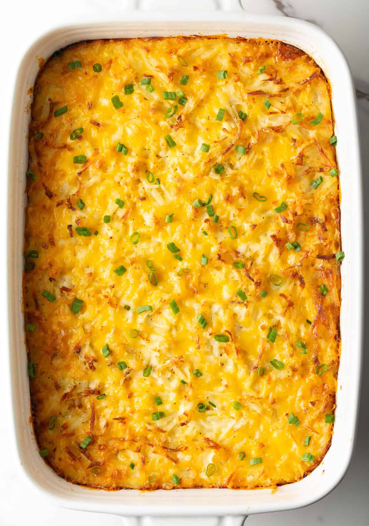 An overhead shot of cheesy hash browns in a casserole dish.