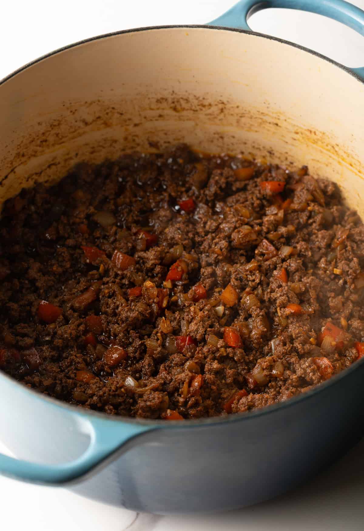 A beef mixture is browning in a pot for a Cincinnati chili recipe.