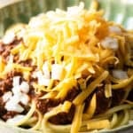 A closeup shot of a classic Cincinnati chili recipe topped with shredded cheese.