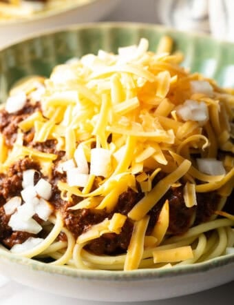 A closeup shot of a classic Cincinnati chili recipe topped with shredded cheese.