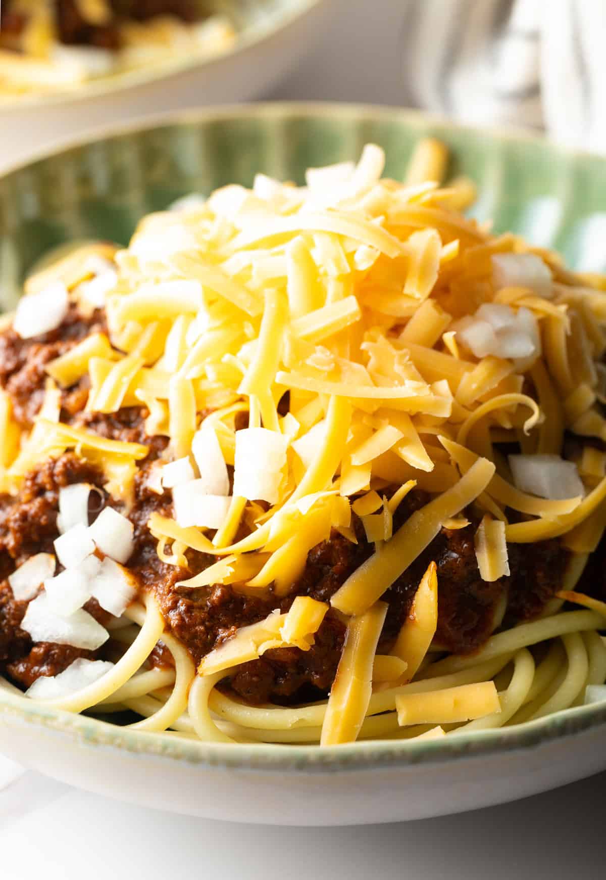 A closeup shot of a classic Cincinnati chili recipe topped with shredded cheese.