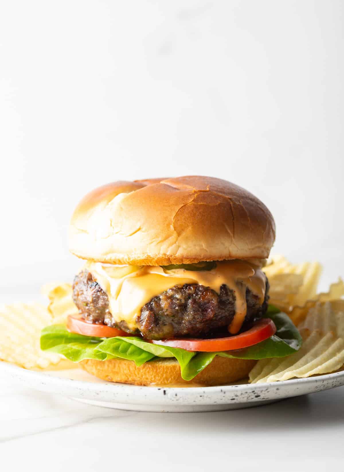 A homemade crack burgers recipe featuring a beef patty between two buns and topped with cheese, lettuce, and tomato.