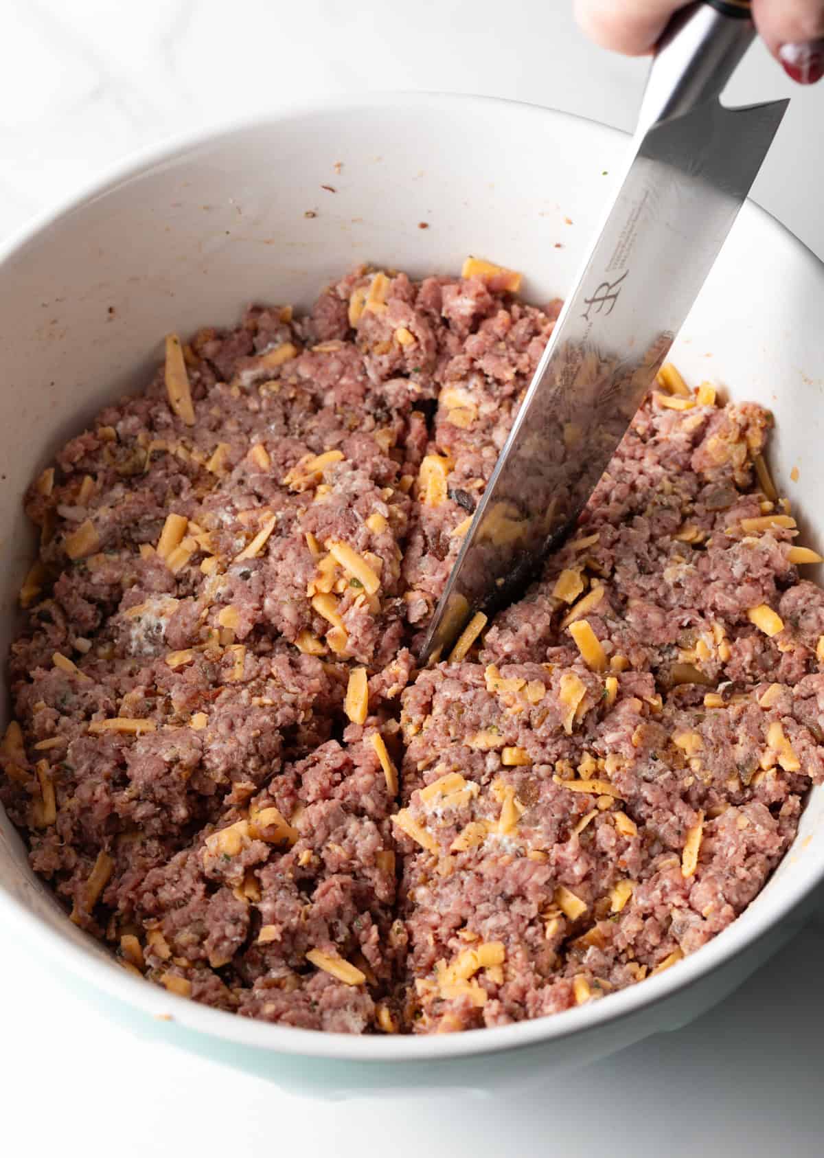 Using a knife to cut a bowl of ground beef into 8 triangles.