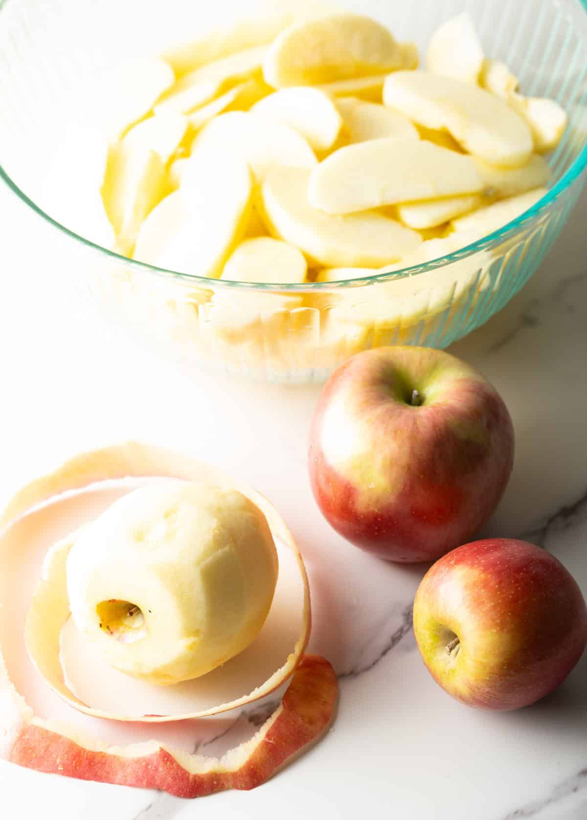 Apples are being peeled and soaked in lemon juice for an easy homemade apple pie recipe.