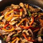 A black skillet filled with steak and pepper fajitas using a homemade fajita marinade.