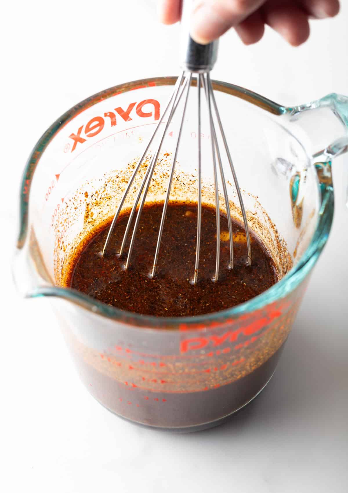 An easy fajita marinade is being whisked in a glass measuring cup.