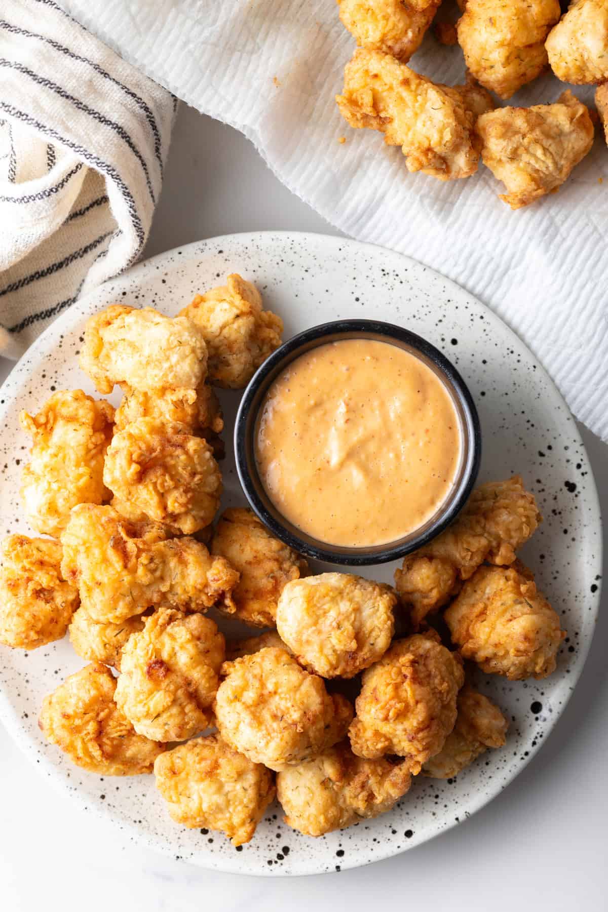 And overhead shot of a plate filled with easy homemade fish bites, sitting next to a ramekin of sauce.