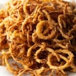 A batch of crispy French fried onions on a white plate.