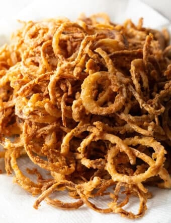 A batch of crispy French fried onions on a white plate.