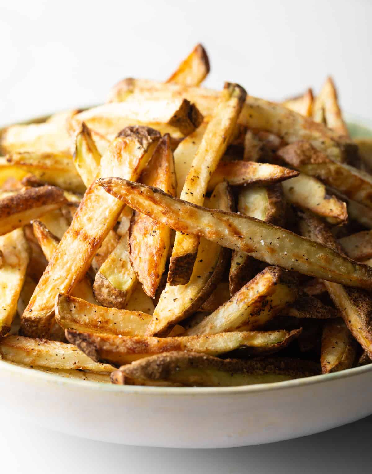 A white bowl filled with crispy homemade fries made in the air fryer.