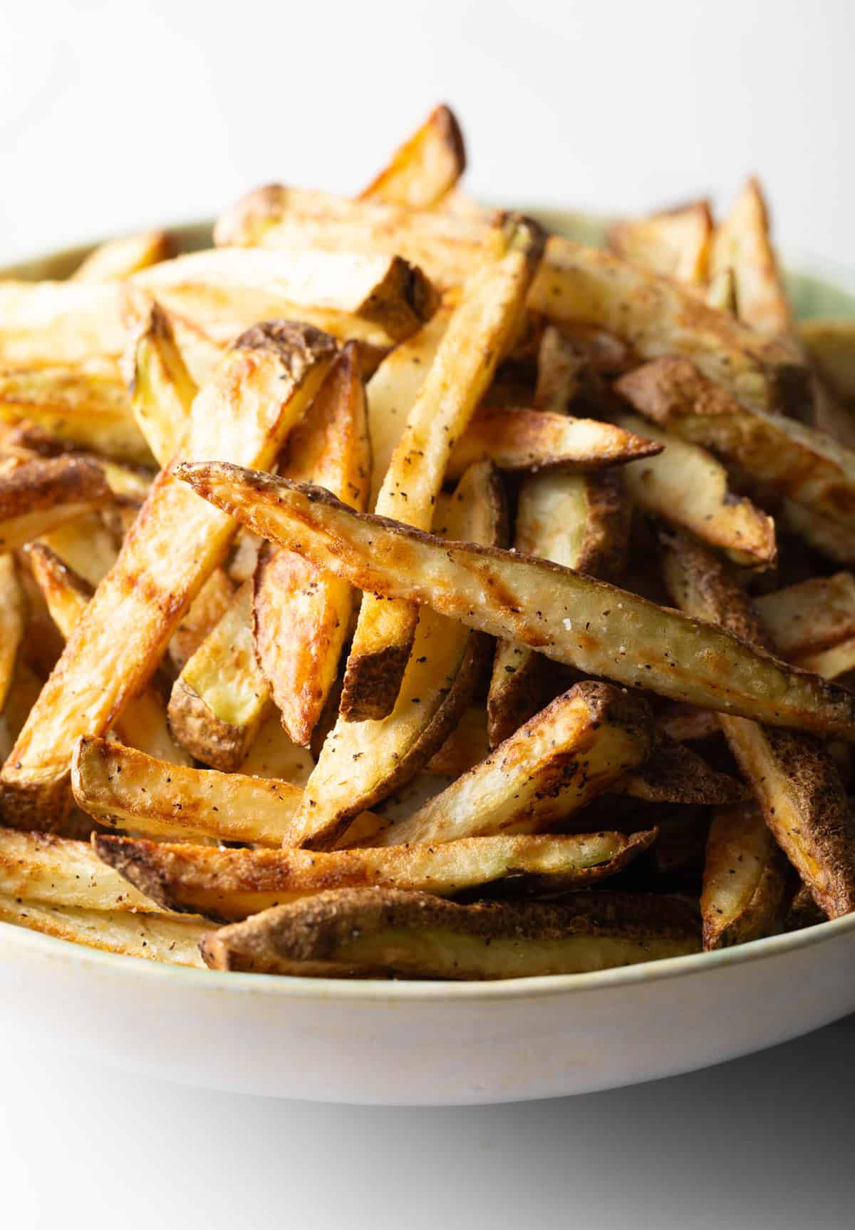 A batch of homemade fries in air fryer in a white bowl.