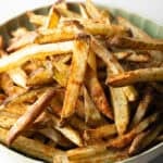A batch of homemade French fries in air fryer in a green bowl.