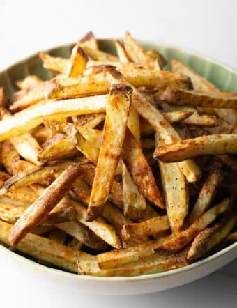 A batch of homemade French fries in air fryer in a green bowl.