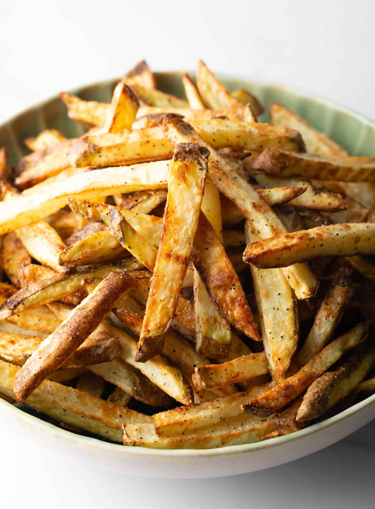 A batch of homemade French fries in air fryer in a green bowl.