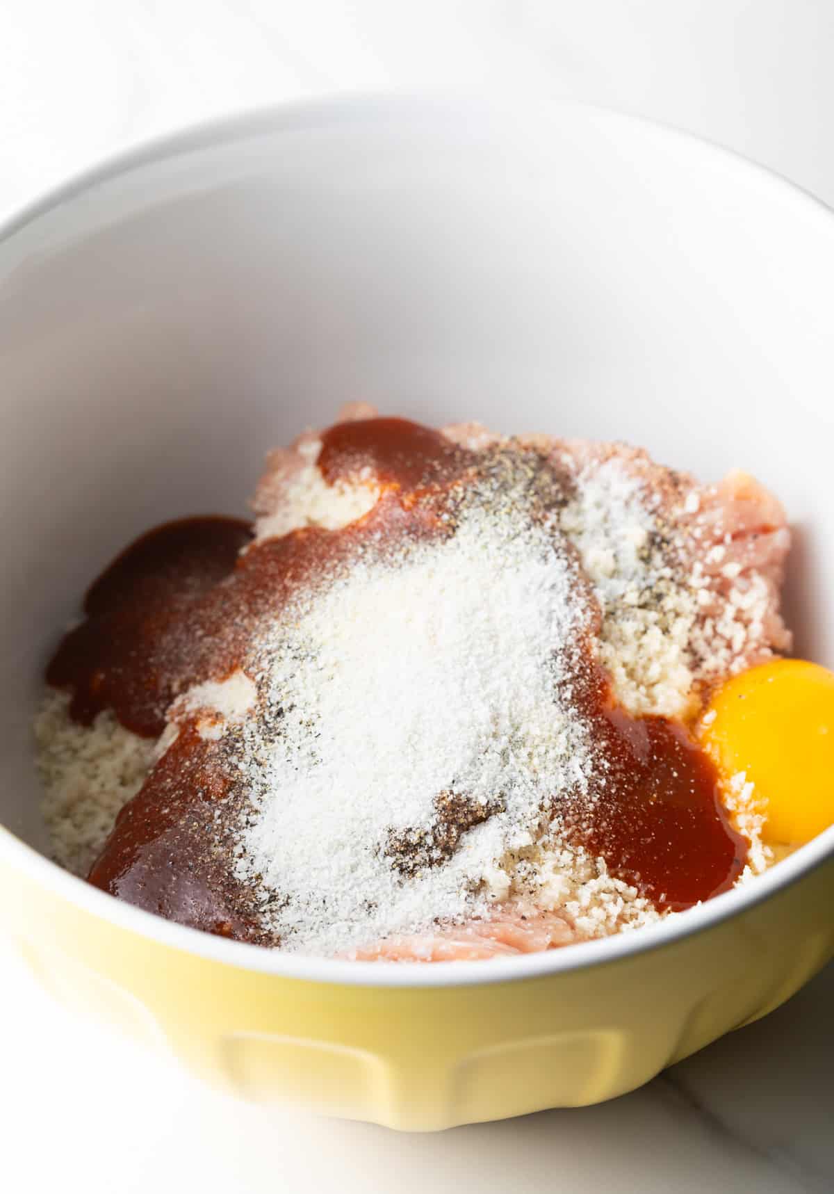 A bbq chicken burgers mixture sitting in a white bowl ready to be mixed together.