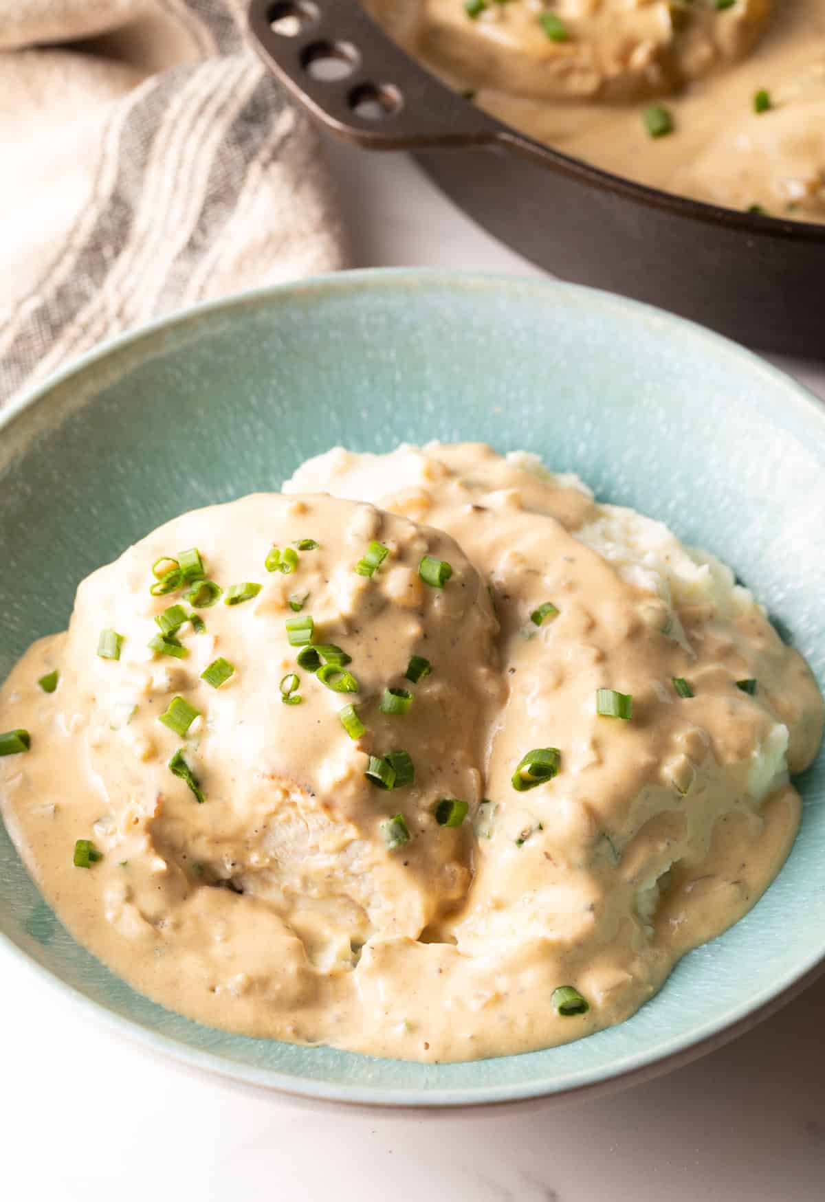 A blue bowl filled with creamy jalapeno chicken topped with green onions.