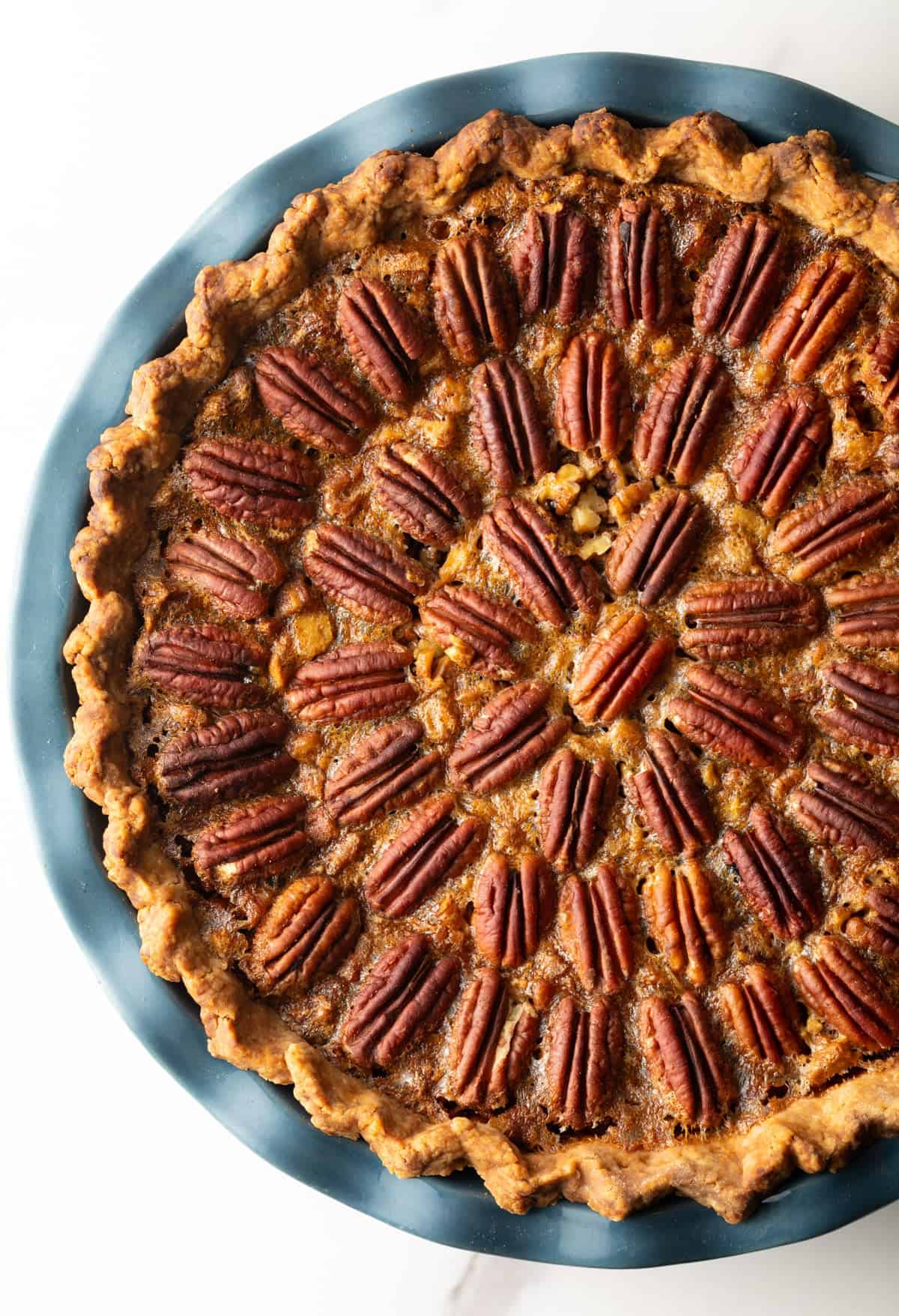A simple pecan pie recipe in a blue pie plate, fresh from the oven.