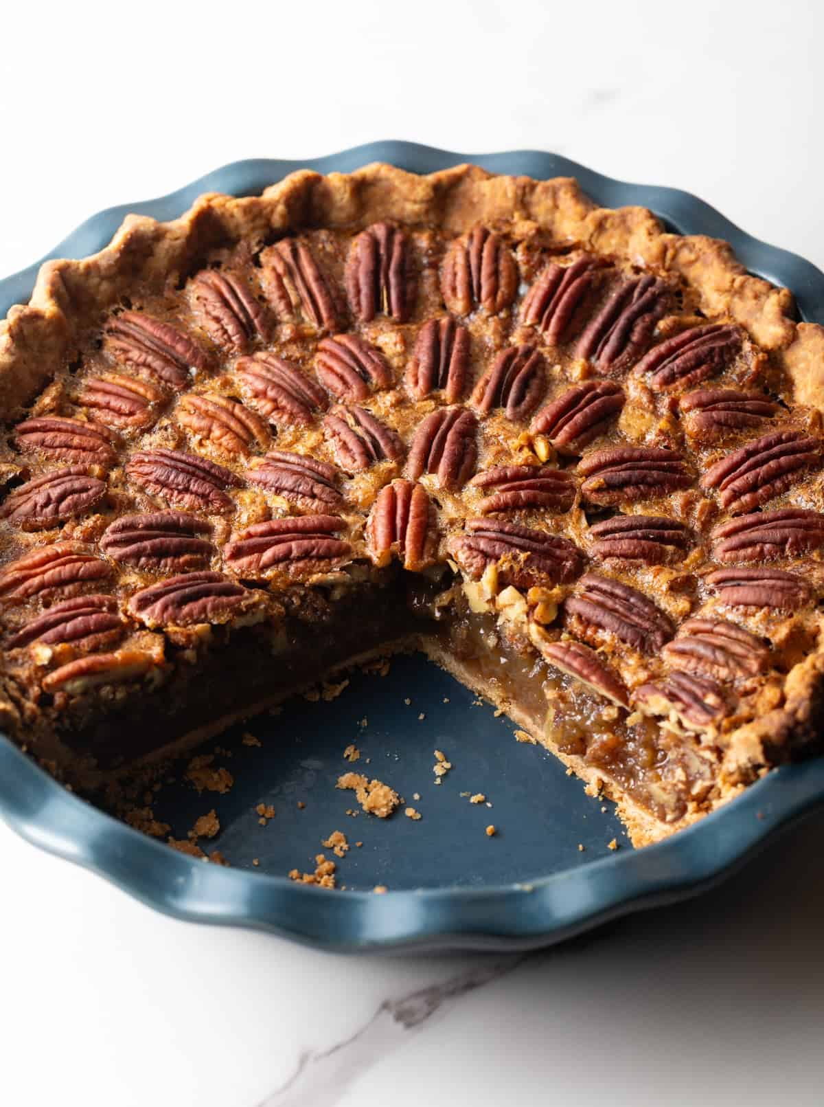 A pecan pie in a blue pie plate with 2 slices taken out, showing the inside.