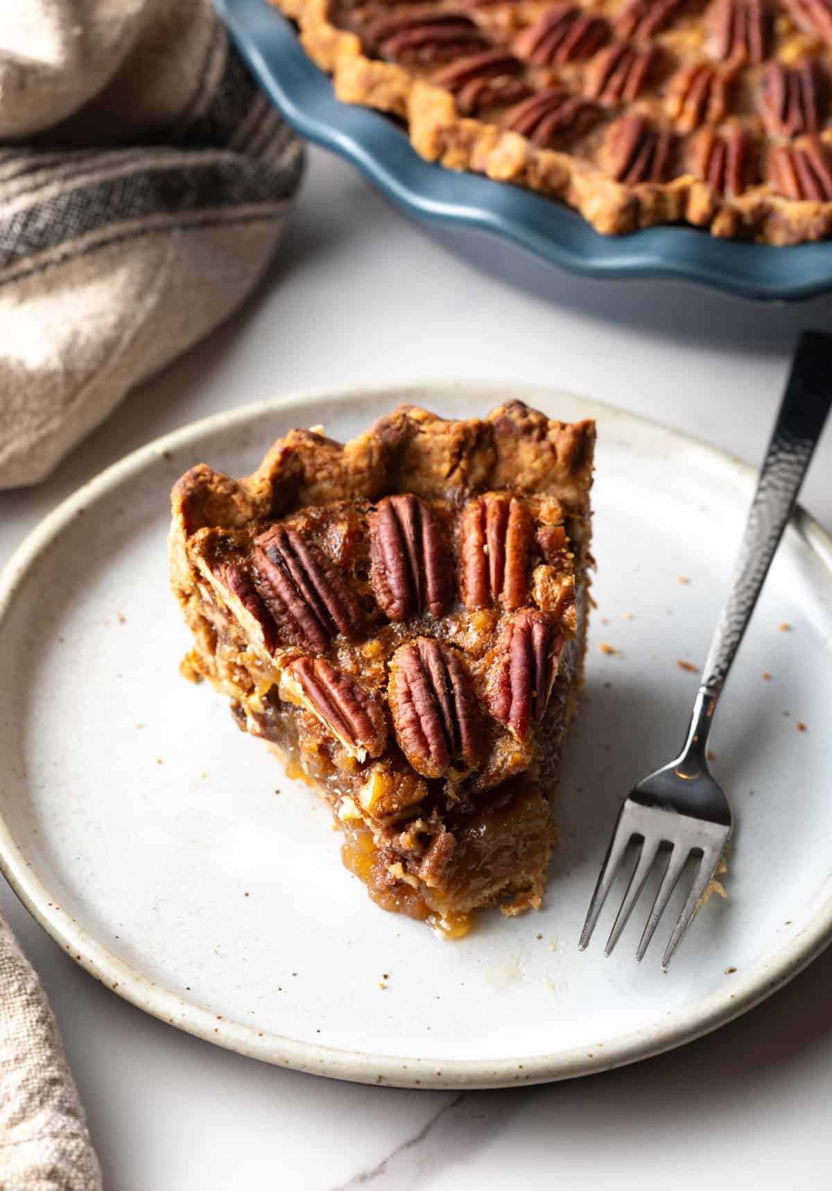 A slice of easy pecan pie on a white plate with a bite taken out of it.