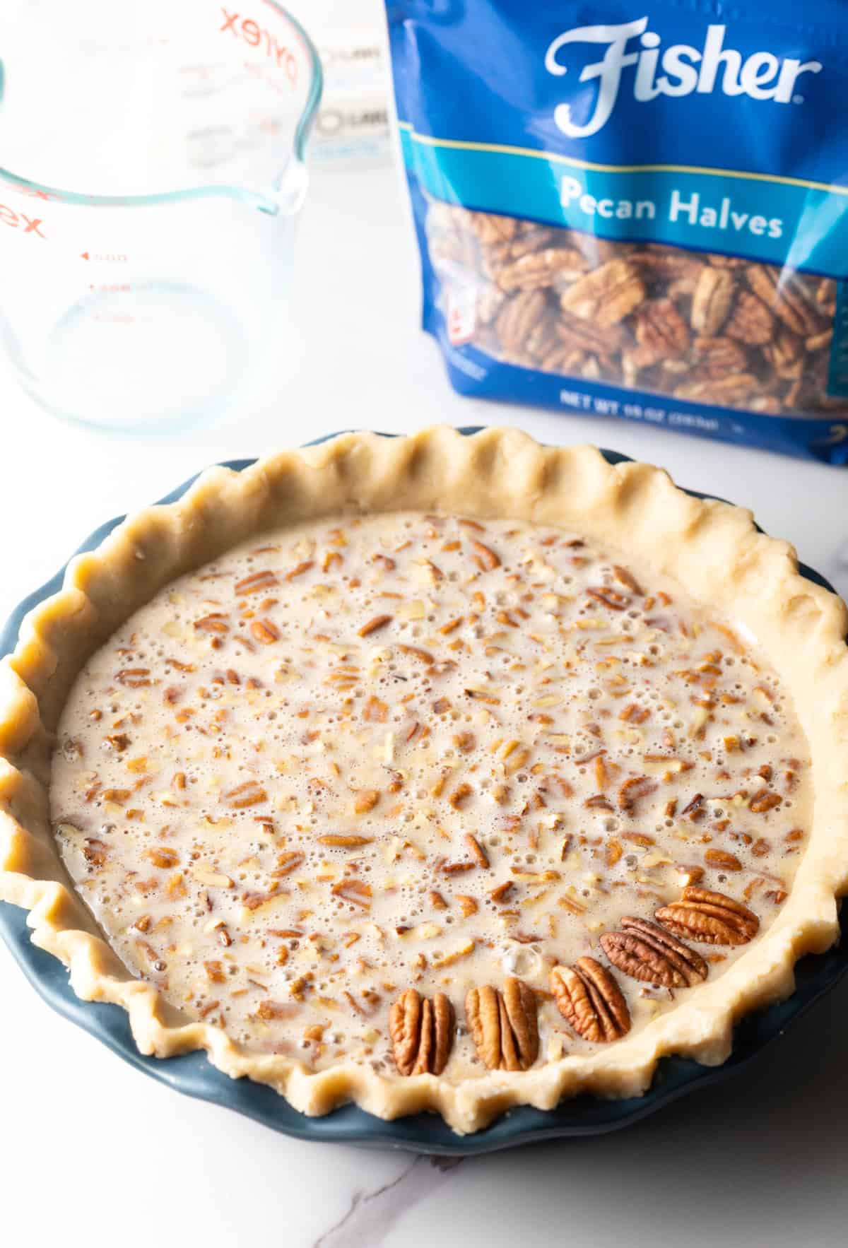 A pie crust filled with a pecan pie filling topped with a few pecan halves.