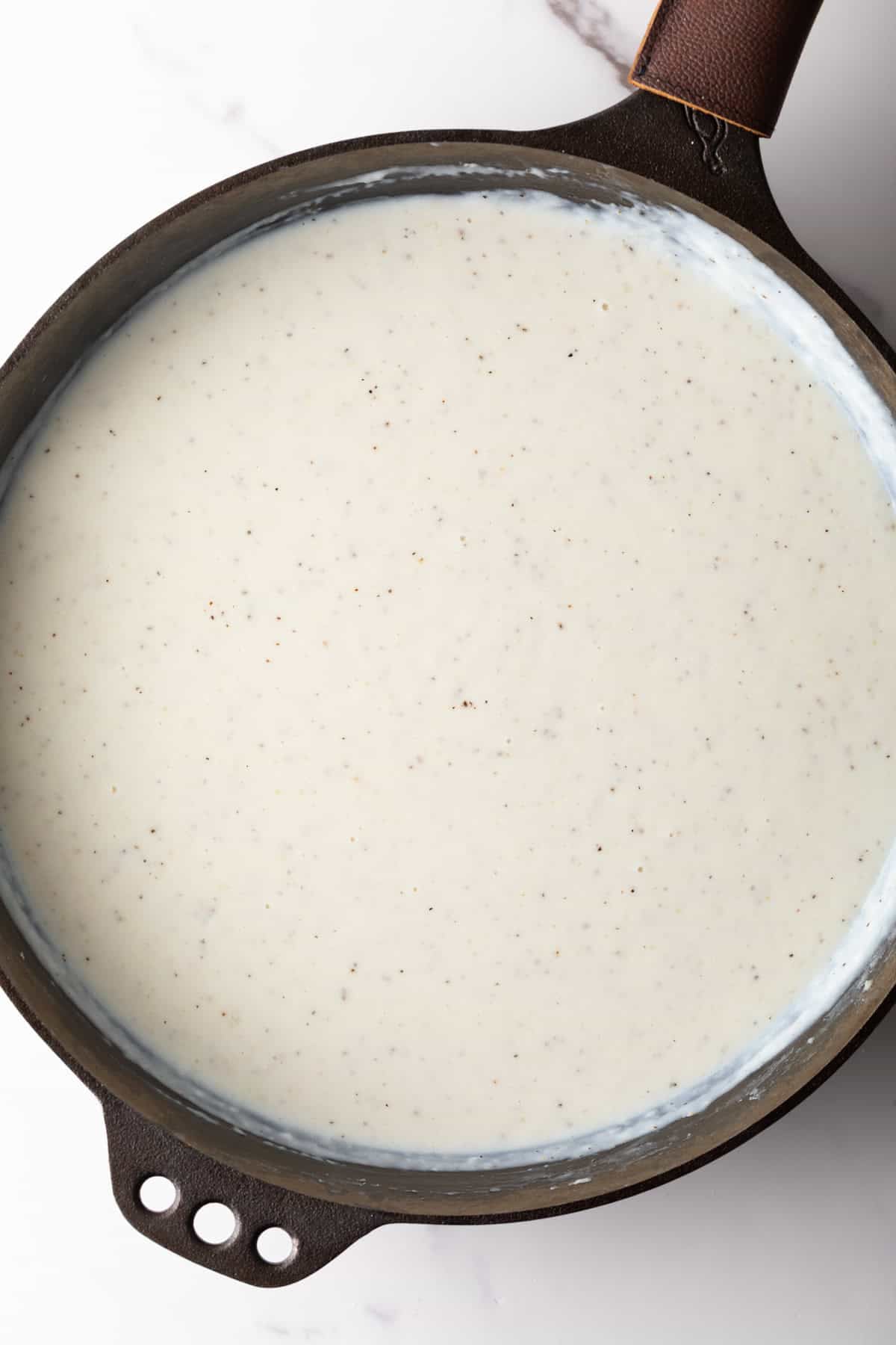 A black skillet is simmering a homemade country gravy recipe.
