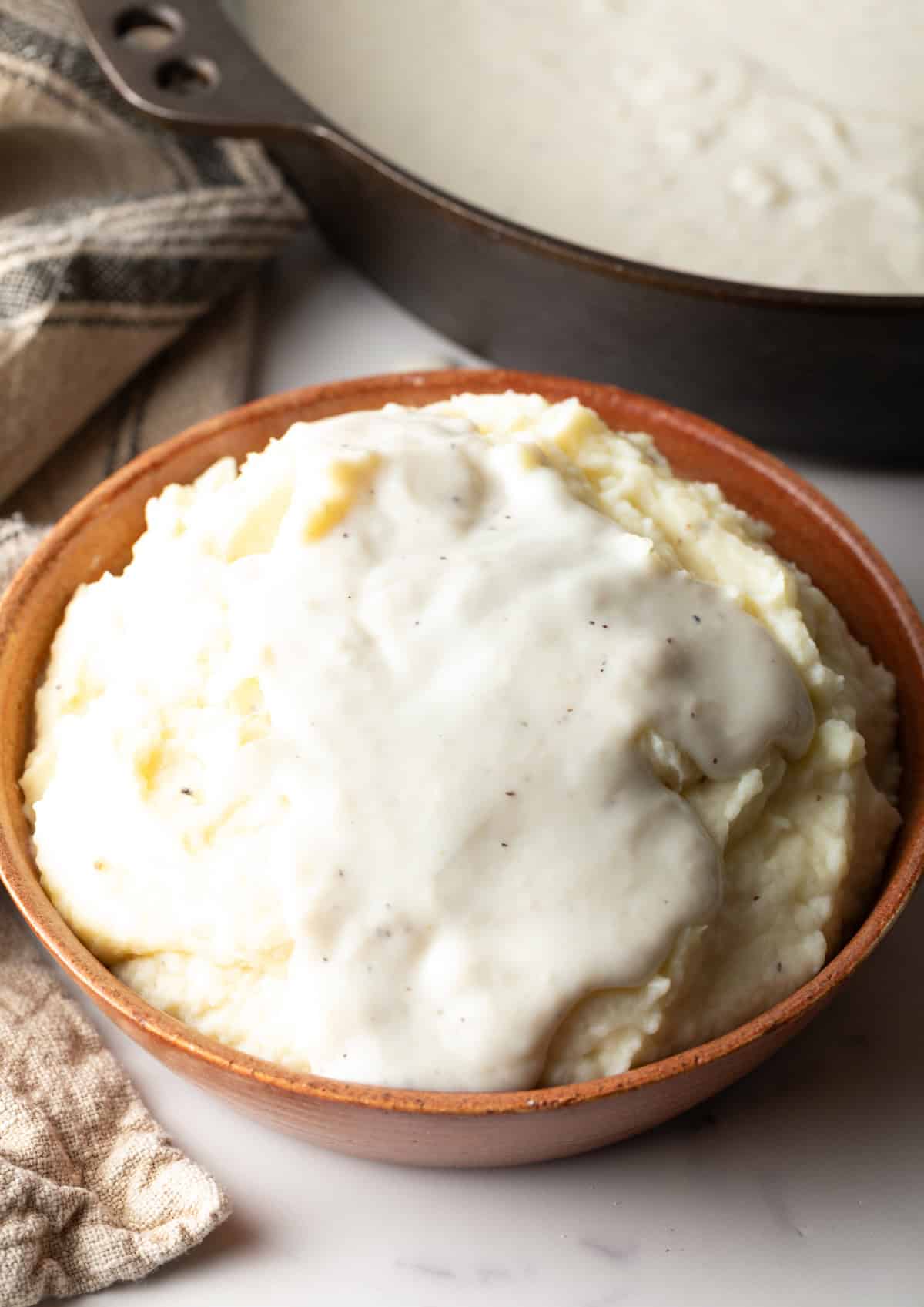 A bowl of mashed potatoes topped with homemade country gravy.