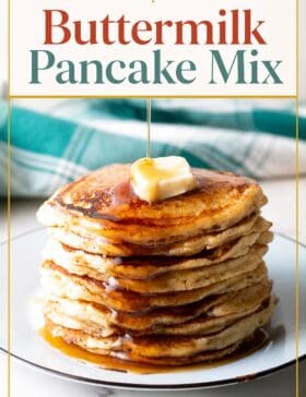 Single-image poster of homemade buttermilk pancake mix in a jar beside a tall stack of golden, fluffy pancakes drizzled with maple syrup, styled in warm amber, deep red, teal, and olive tones.