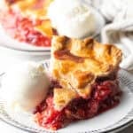 A slice of strawberry rhubarb pie with a scoop of vanilla ice cream on the side.