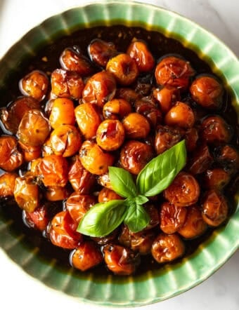 roasted cherry tomatoes in green bowl with basil